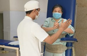 Kỹ thuật viên hướng dẫn người bệnh bài tập phục hồi chức năng vận động tay chân cho bệnh nhân bị u tuỷ ngực